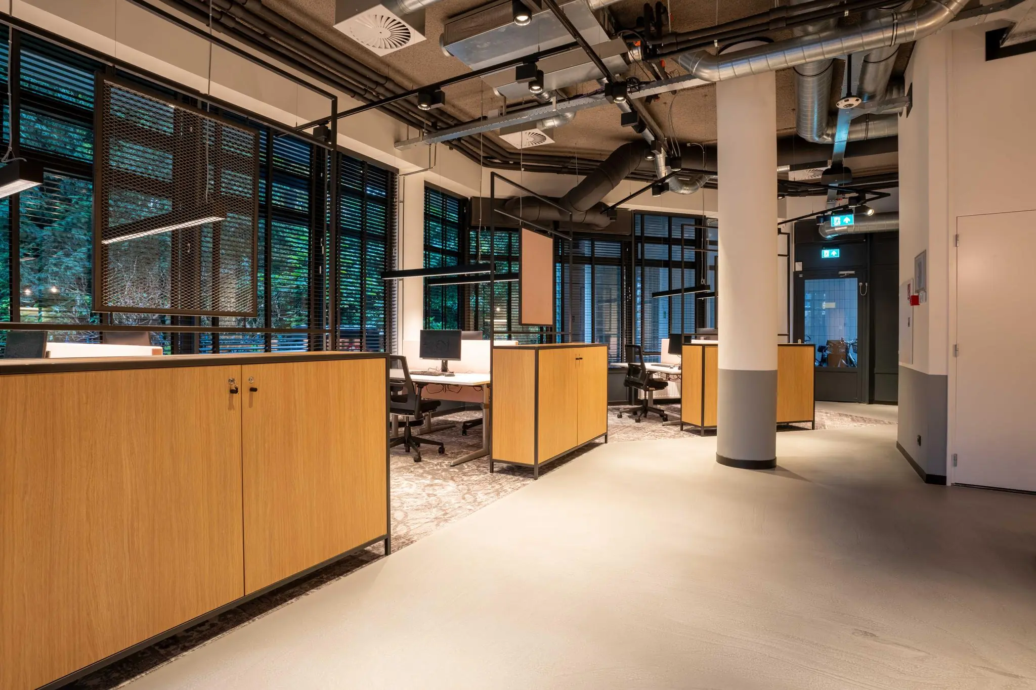 Modern kantoorinterieur aan de 1e Hogeweg met open werkplekken, houten kasten en industriële plafondafwerking.